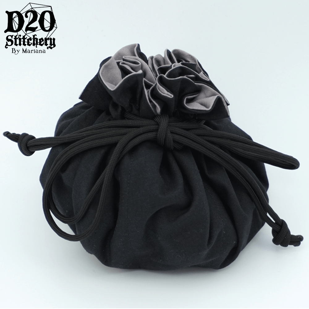 Epic dice bag with neutral grey lining and black exterior fabric tied with black paracord.