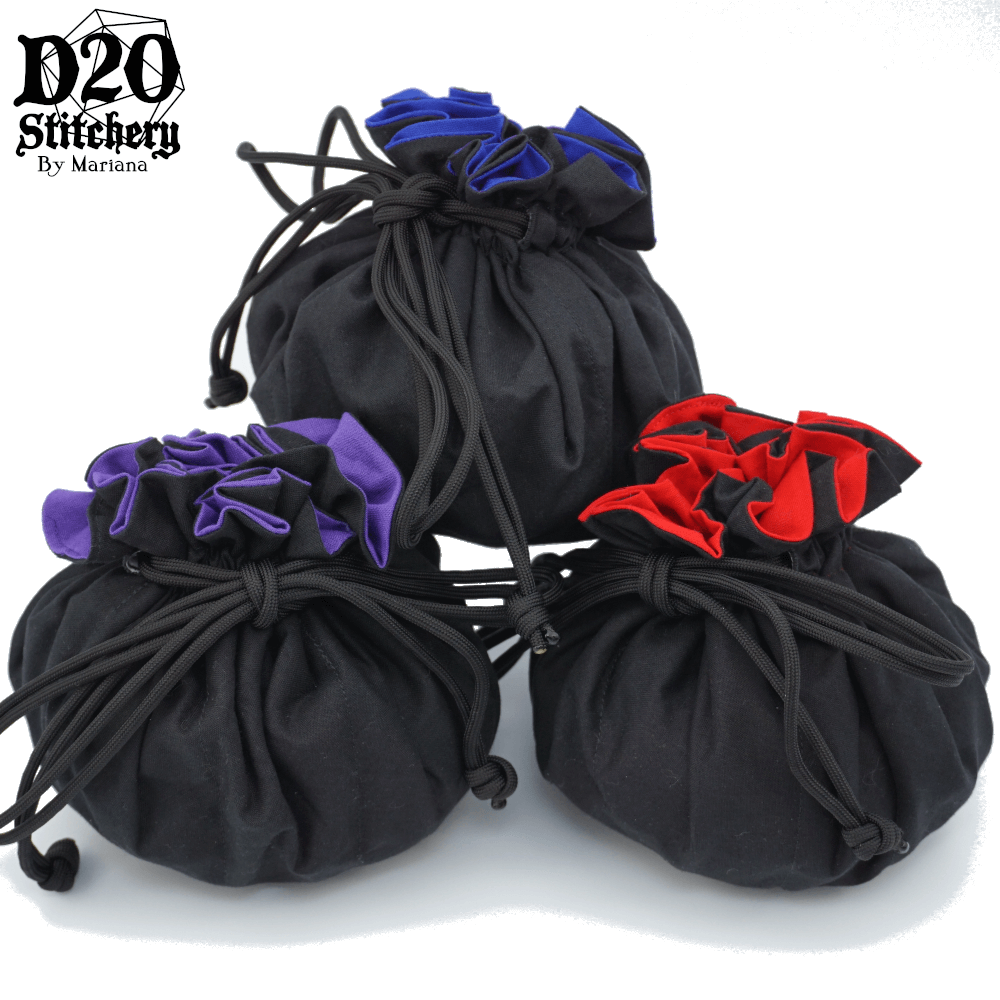 3 Epic dice bags with black exterior fabric, one with blue lining, one with purple lining and one with red lining tied with black paracord.