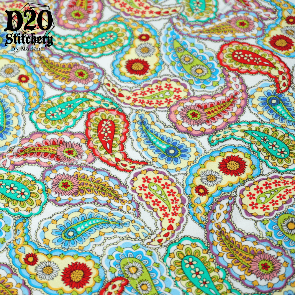 Photo of flat fabric of various colorful paisleys on a white background to show the pattern of the fabric.  Many paisleys have sunflowers, daisies, or hearts inside. The colors are bright and cheery, yellows, teals, blues, reds and purples.